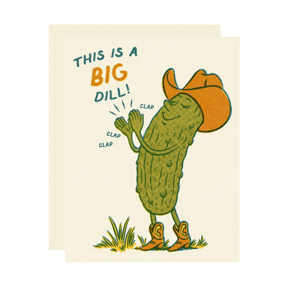 A greeting card with a cream background featuring a cartoon pickle dressed in an orange cowboy hat and boots, clapping his hands. The text on the card reads 'THIS IS A BIG DILL!' in dark teal and orange.