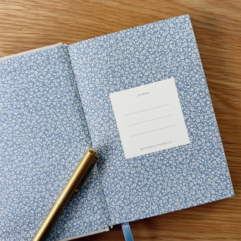 First page of journal with a blue and white floral background. Contains a white box with the words "JOURNAL" and three lines.