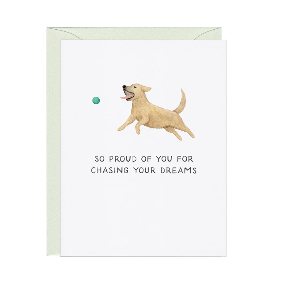 Greeting card with a dog chasing a ball and text that reads "So proud of you for chasing your dreams" on a white background