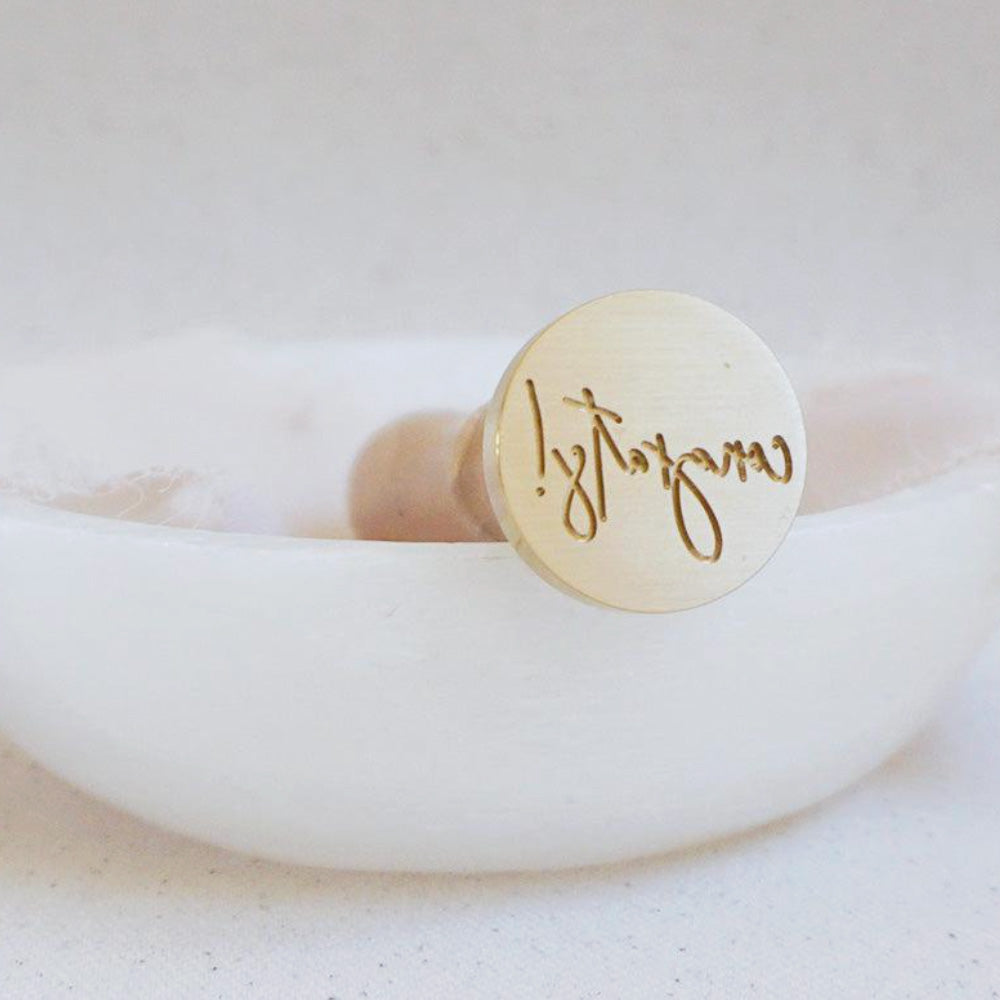 Gold wax seal with the word Congrats! on it in cursive