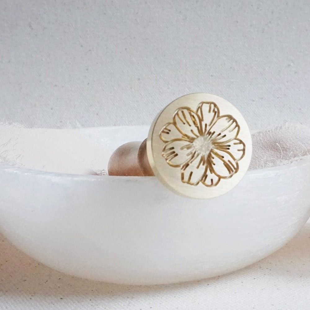 Gold wax seal head with a cosmo flower on it