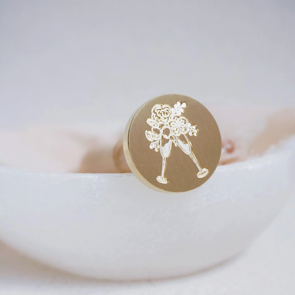 Gold wax seal head with two champagne flutes and flowers