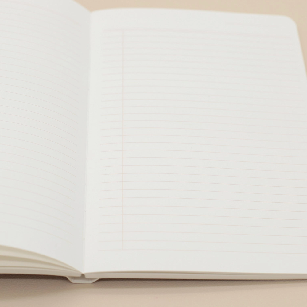 An open lined notebook with blank white pages, photographed on a plain beige surface.