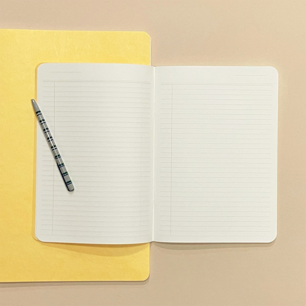 An open lined notebook with white pages lies on a yellow folder against a warm beige background, with a striped pen resting on the left page.