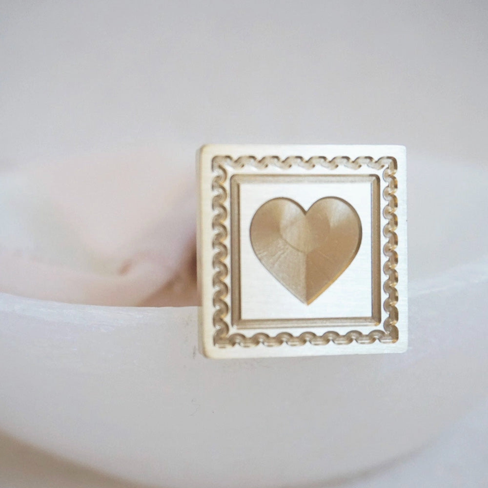 Gold wax seal of a postage stamp with a heart in it