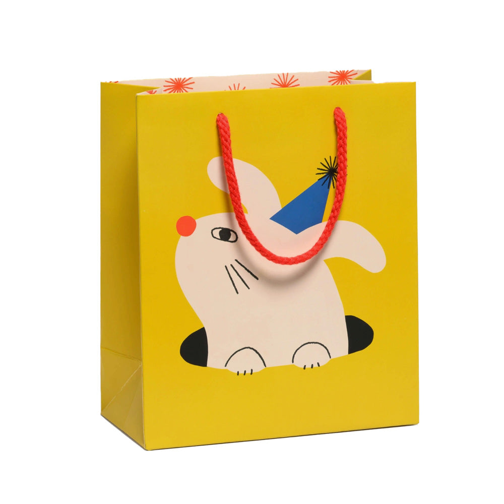Yellow gift bag with a cartoon bunny wearing a party hat on a white background