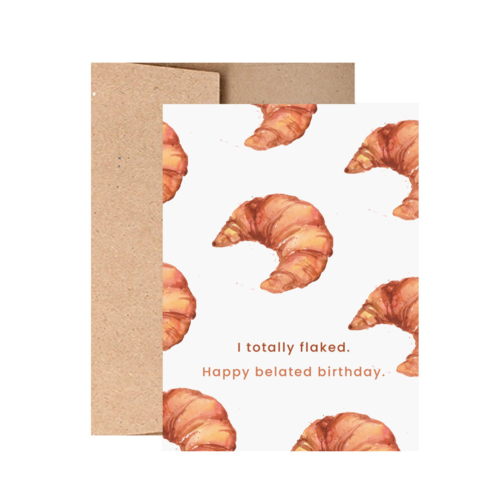 Greeting card with croissant design and text reading "I totally flaked. Happy belated birthday." on a white background