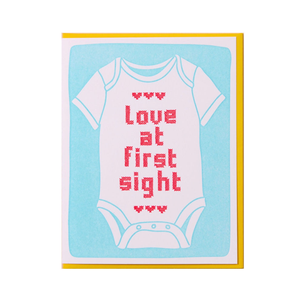 Card with a baby onesie design and 'Love at First Sight' text on a light blue background.