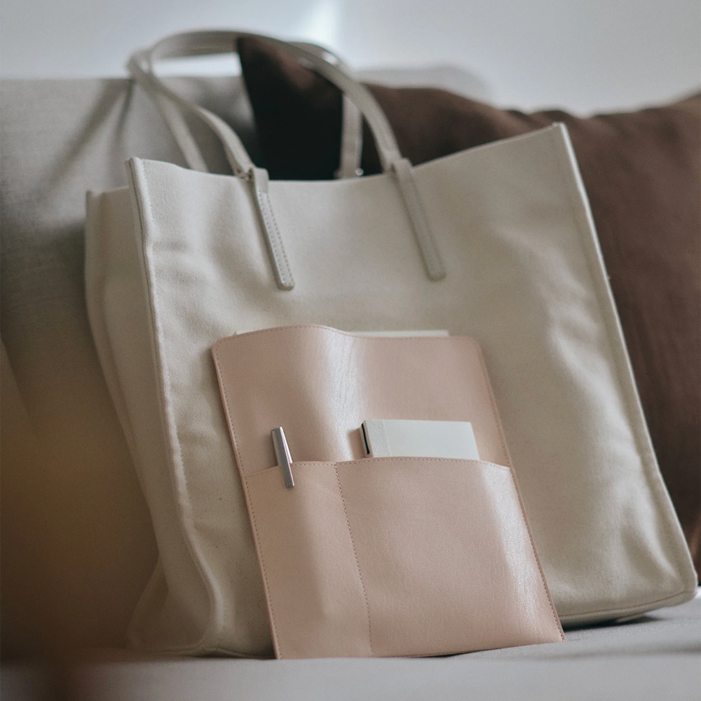 Beige tote bag with a leather notebook bag on a neutral background