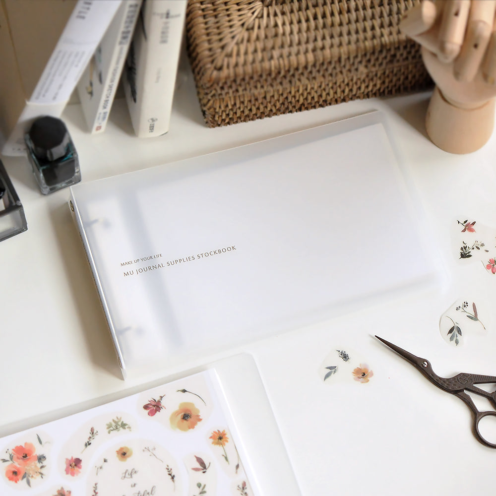 Stationery items including a notebook, floral cards, and scissors on a desk.