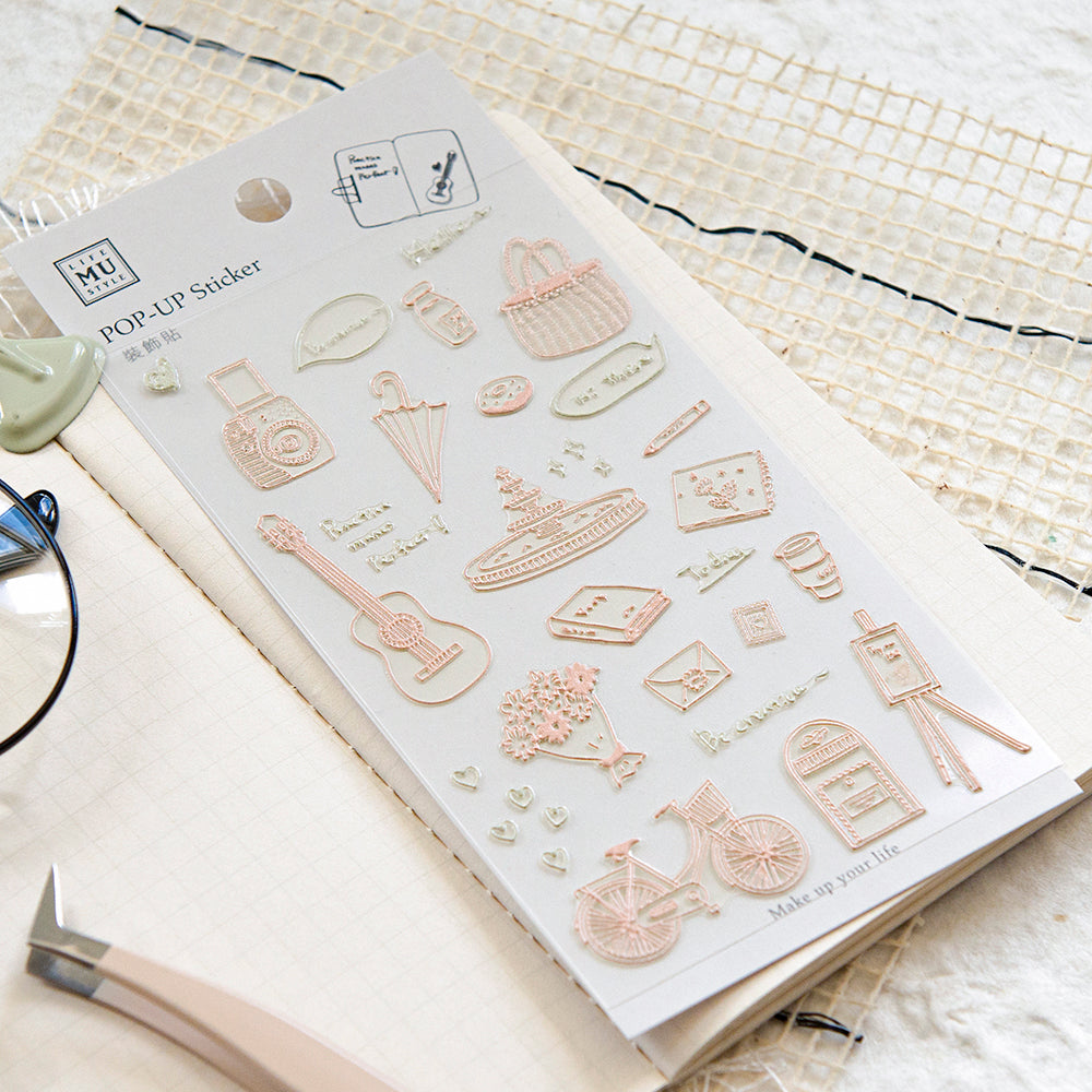 Sheet of pop-up stickers with various small objects on a textured surface