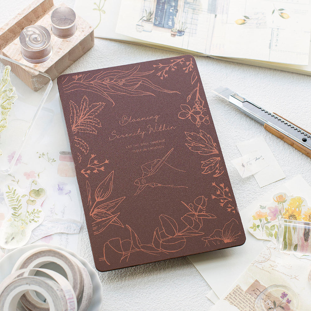 Brown cutting mat with floral patterns on a light surface with stationery items