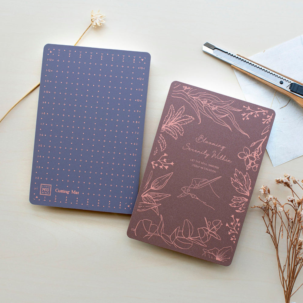 Cutting mat front side brown with floral design and backside is blue with a grid pattern on a light surface.