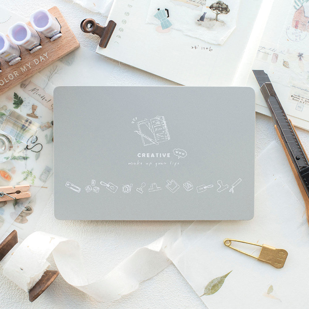 Gray cutting mat with 'Creative' design on a desk with stationery items