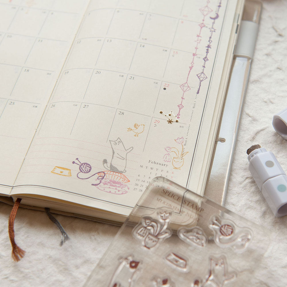 Open planner with decorative elements and a clear stamp set on a textured surface