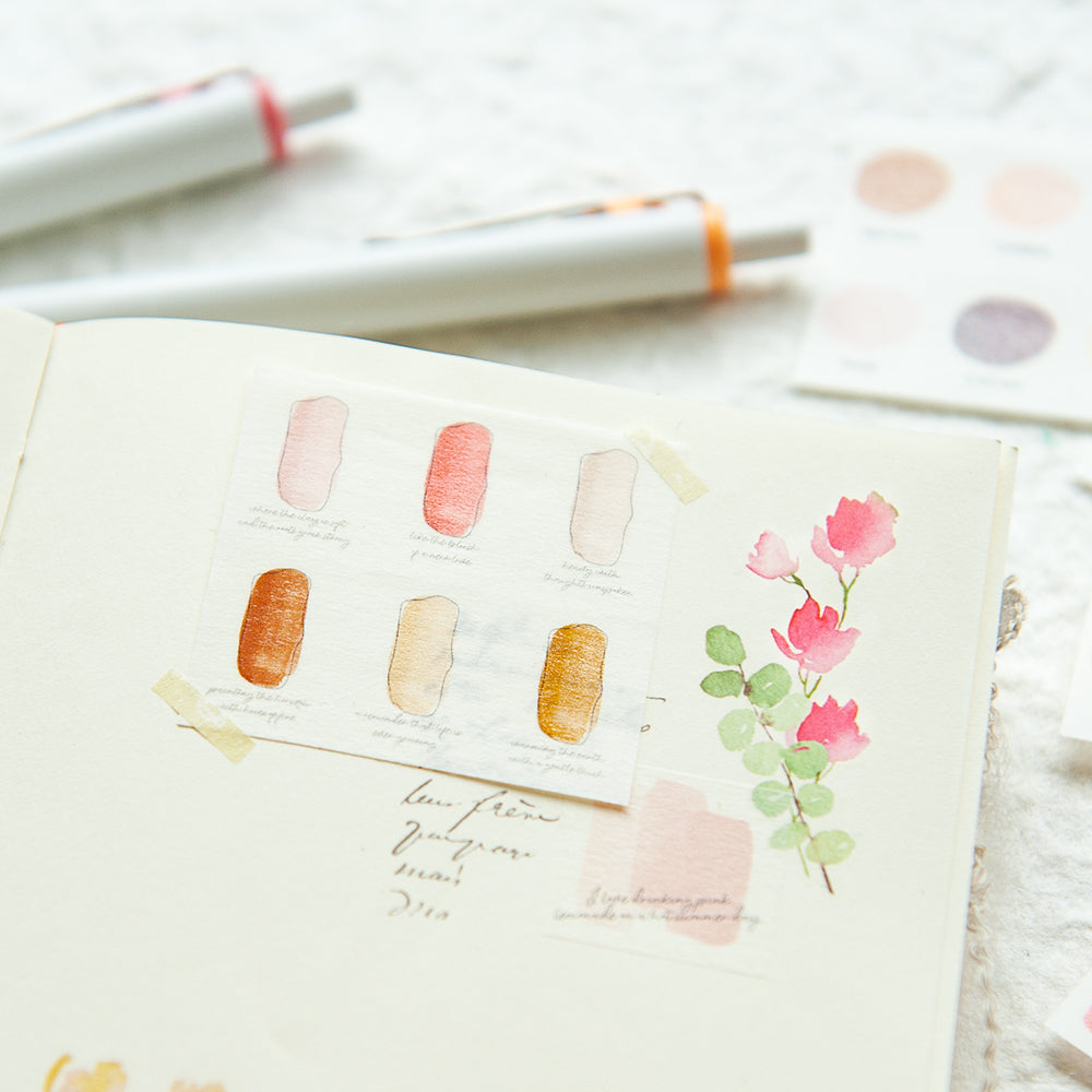 Notebook with watercolor designs and pens on a light background