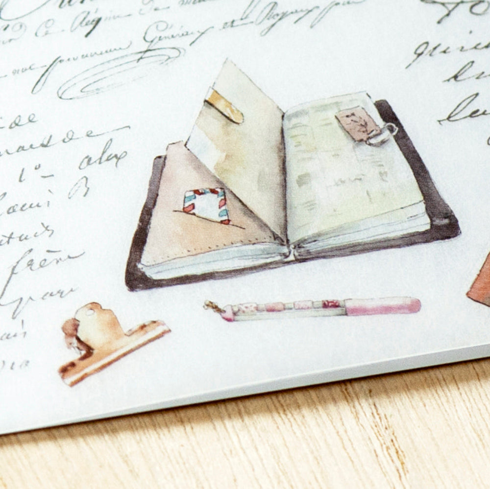 Decorative stationery set with an open book, pen, and letter opener on a textured surface.