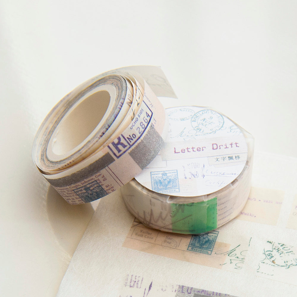 Two rolls of decorative tape with postage stamp designs on a white surface.