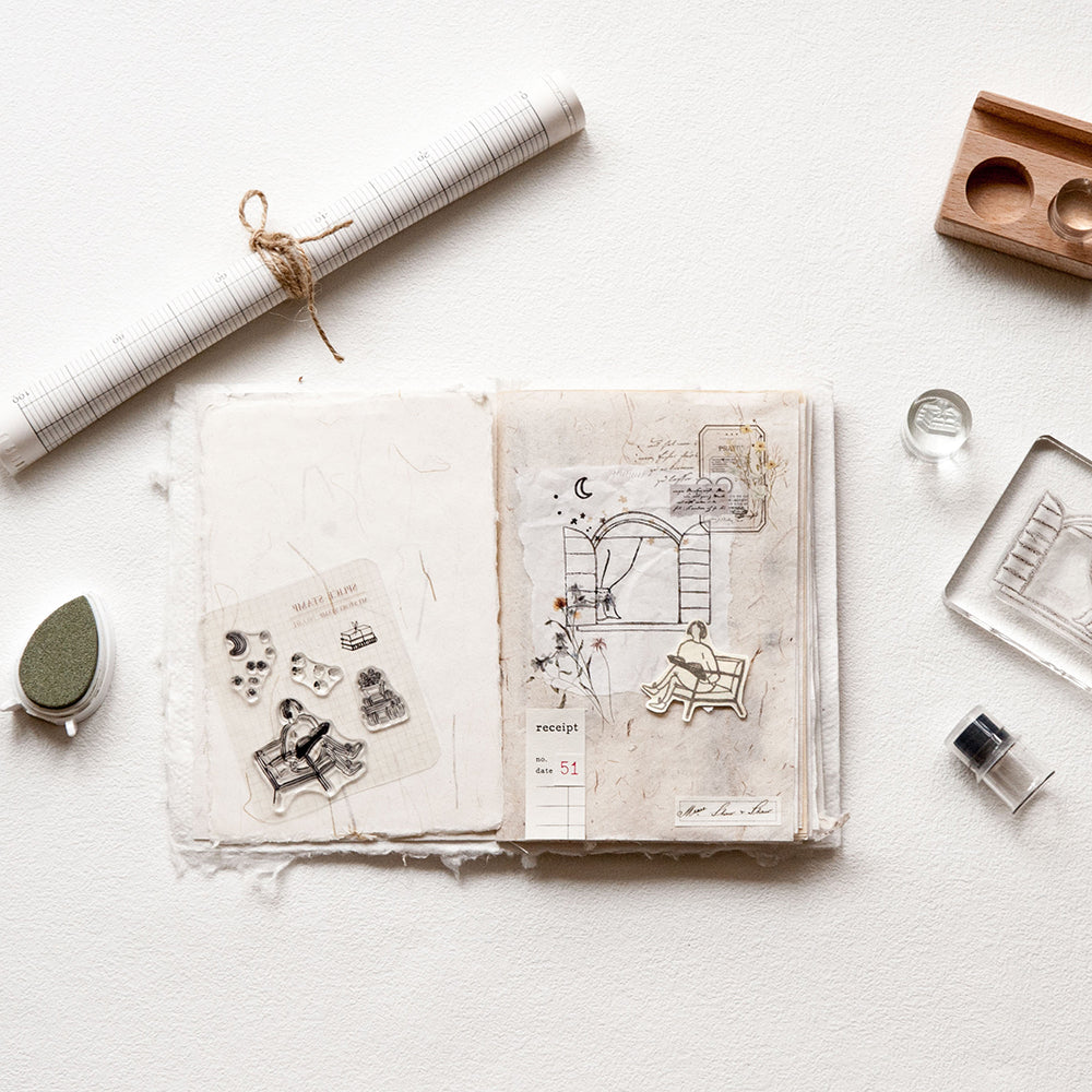 Open notebook with illustrations on a light surface with stationery items.