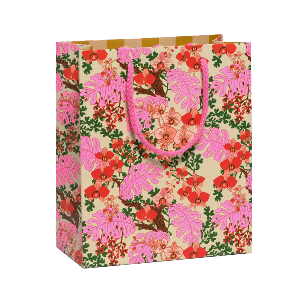 Floral patterned paper bag with pink handles on a white background