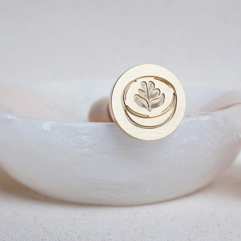 Gold wax seal head of a matcha mug with latte art in the middle