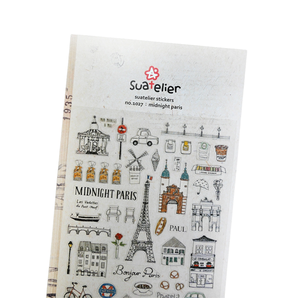 A sheet of Suatelier stickers labeled 'midnight paris', featuring black and gray illustrated Paris-themed motifs such as the Eiffel Tower, street signs, cafés, bicycles, and postcards on a white backing card.
