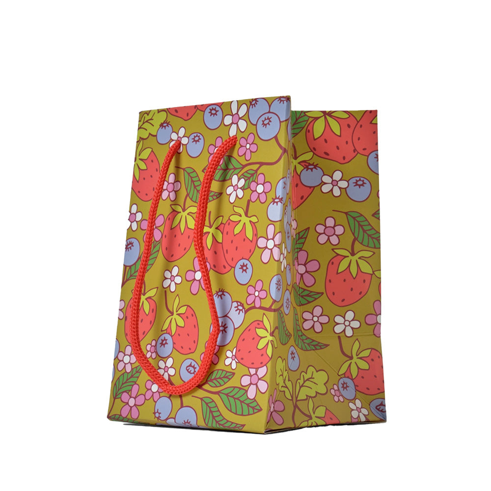 Colorful paper gift bag with strawberry and floral pattern on a white background