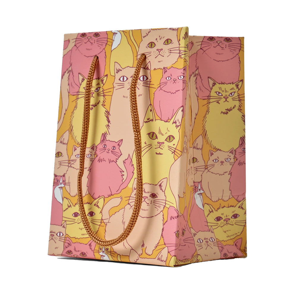 Colorful gift bag with multiple cats on it in yellow, tan, and pink with an orange background.