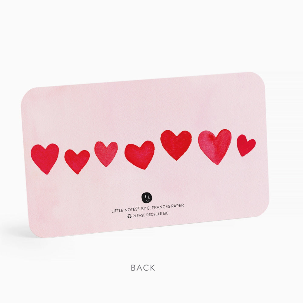 Pink card with red hearts and branding on a white background