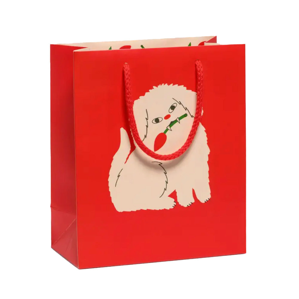 Red gift bag with a white dog with little fangs holding a rose bud in his mouth