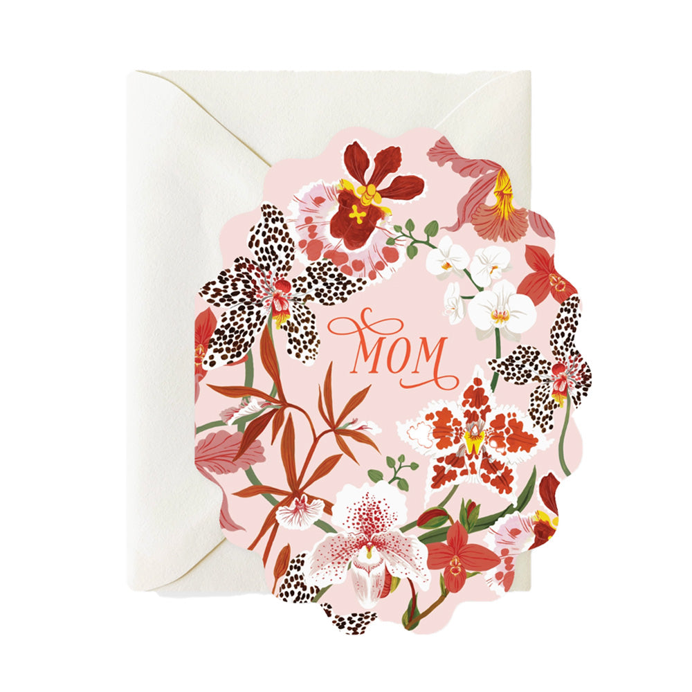 An oval scalloped-edge card with a pale pink background. The background is filled with different orchids of multiple designs with the word "Mom" in the center in a script font.