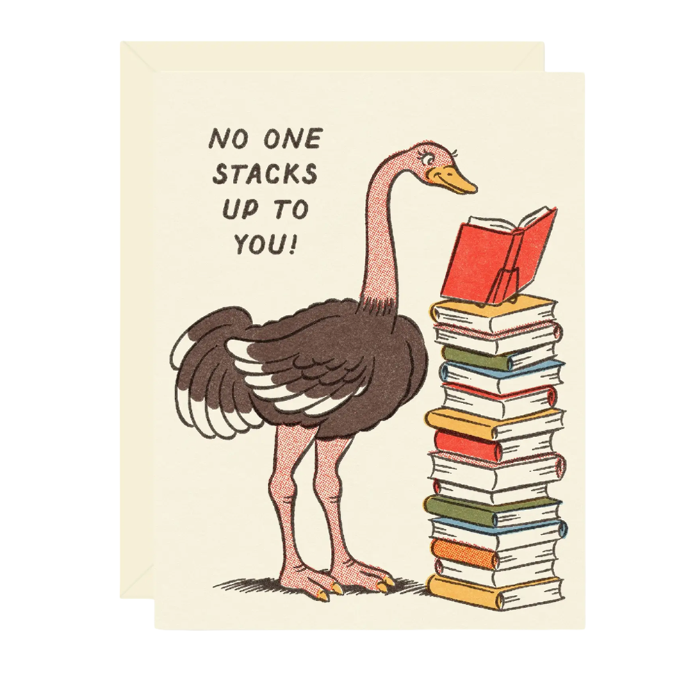 A cream-colored greeting card featuring a vintage-style illustration of a pinkish-brown ostrich standing next to a tall stack of colorful books with a red open book on its head. The text on the card reads, 'NO ONE STACKS UP TO YOU!'.