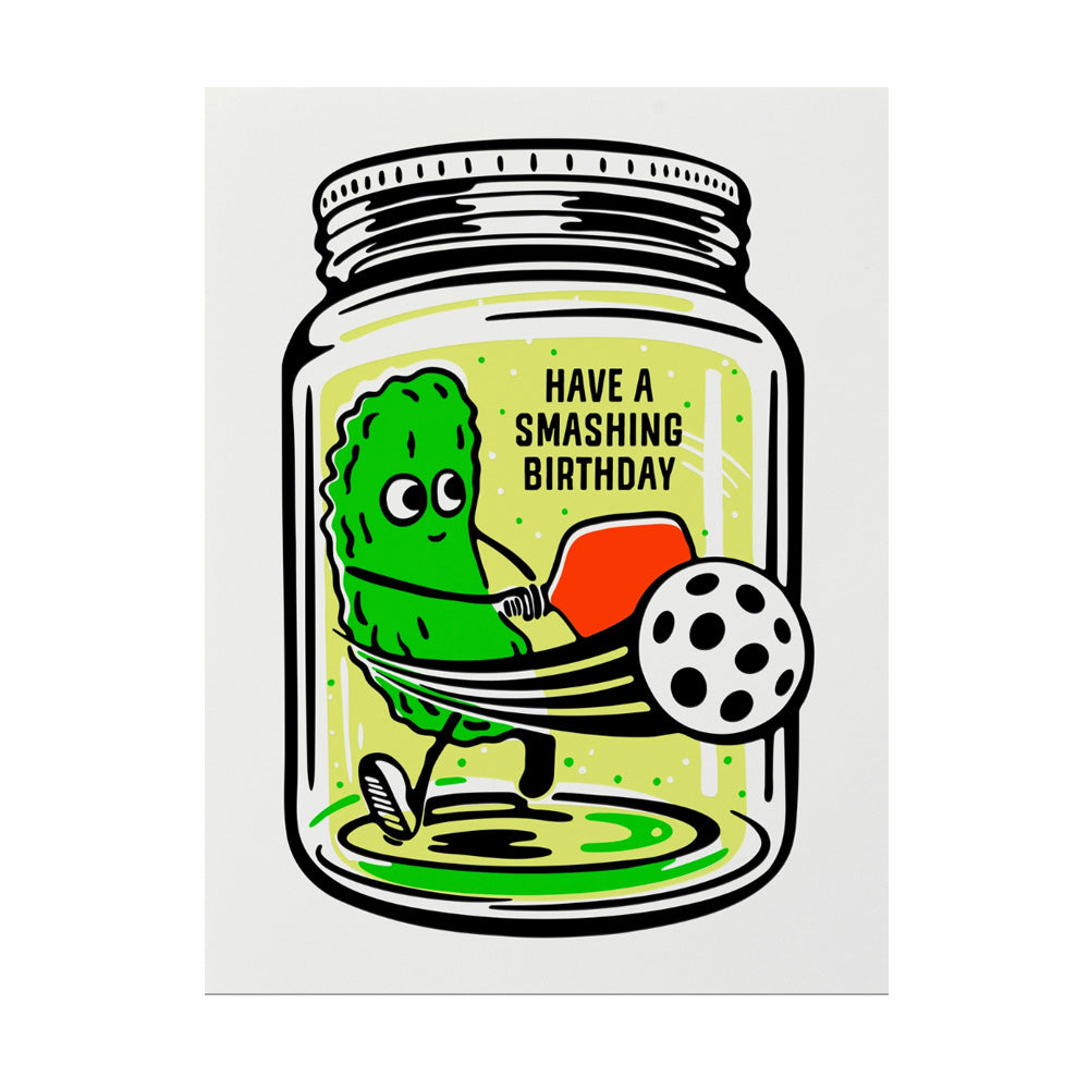 Pickle jar with a pickle inside playing pickleball with text "Have a smashing birthday"