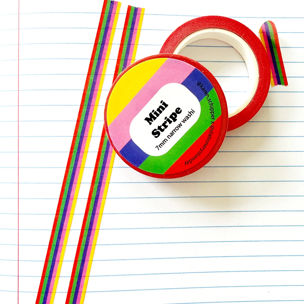 A roll of narrow multi-colored washi tape. The tape features repeating vertical stripes in yellow, orange, red, green, blue, and purple.