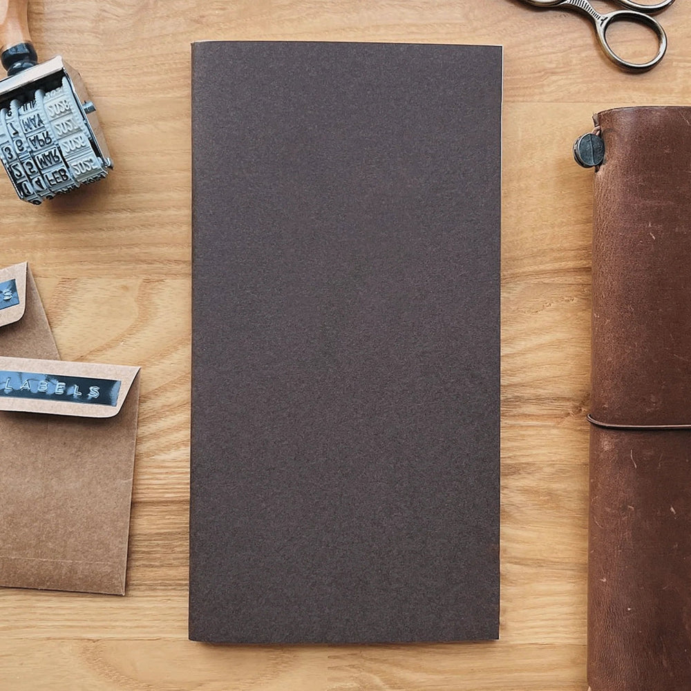 Dark gray notebook with stationery items on a wooden background