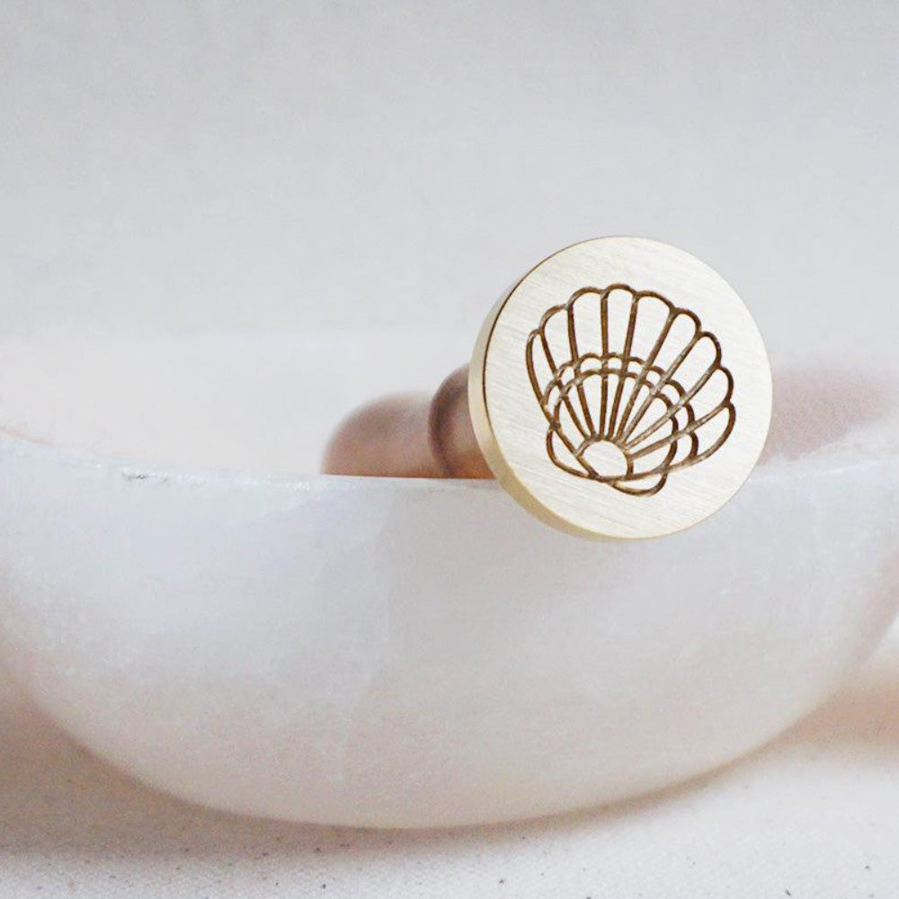 Gold wax seal head with a shell outline design on it