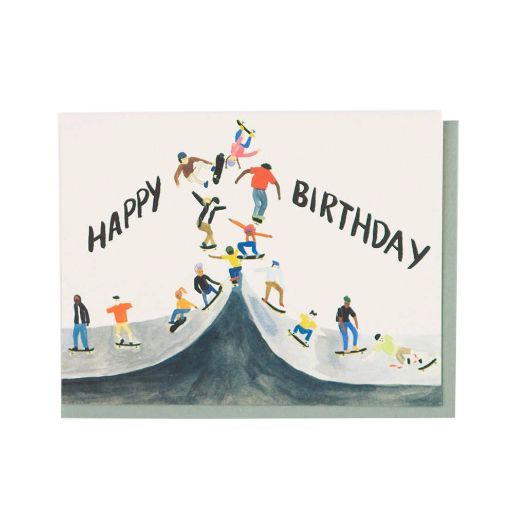 Birthday card with illustration of people skateboarding on a ramp, text 'Happy Birthday' above.