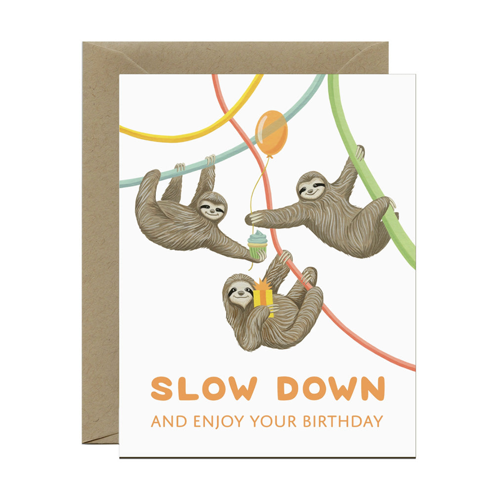 Greeting card with sloths and birthday message, "slow down and enjoy your birthday" on a white background
