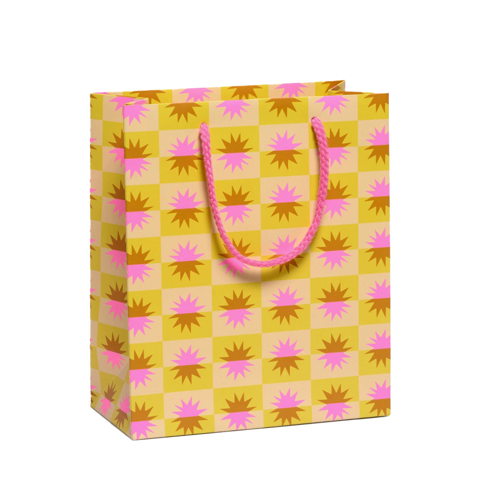Yellow gift bag with pink and brown star pattern and handle on a white background