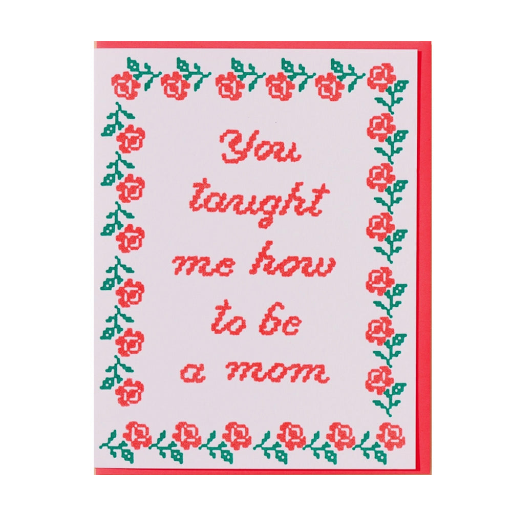 Embroidered text card with floral border and text, "You taught me how to be a mom" on a white background