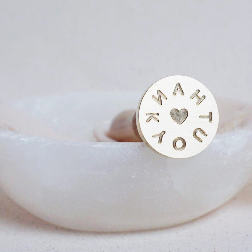 Gold wax seal head of the words "THANK YOU" in a circle with a heart in the middle