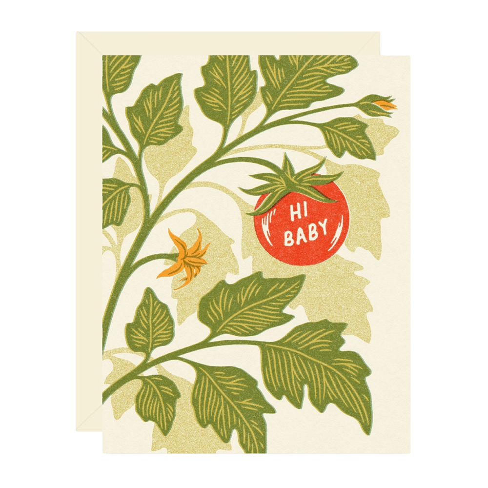 A card with a cream envelope behind it, featuring a stylized botanical illustration of green leaves and stems with a red tomato and a small yellow flower. The tomato has the words “HI BABY” printed on it.