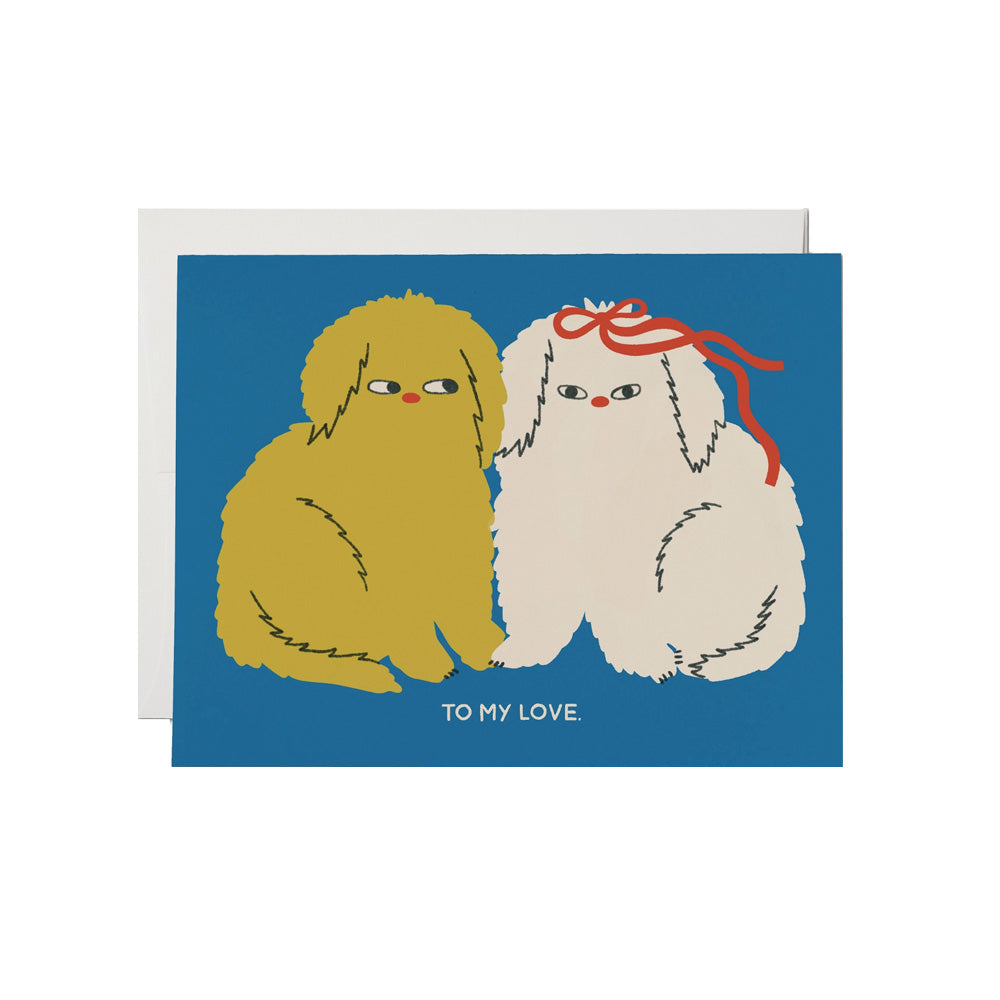 Greeting card with two cartoon dogs, one yellow and one white with a red bow, on a blue background. Text reads, "To my love." on the bottom.