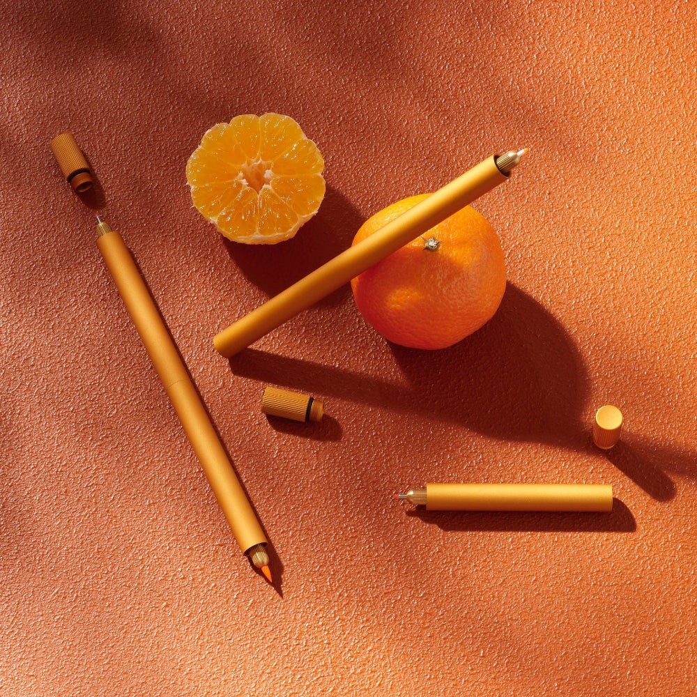 Orange fruits and pens on a textured orange surface