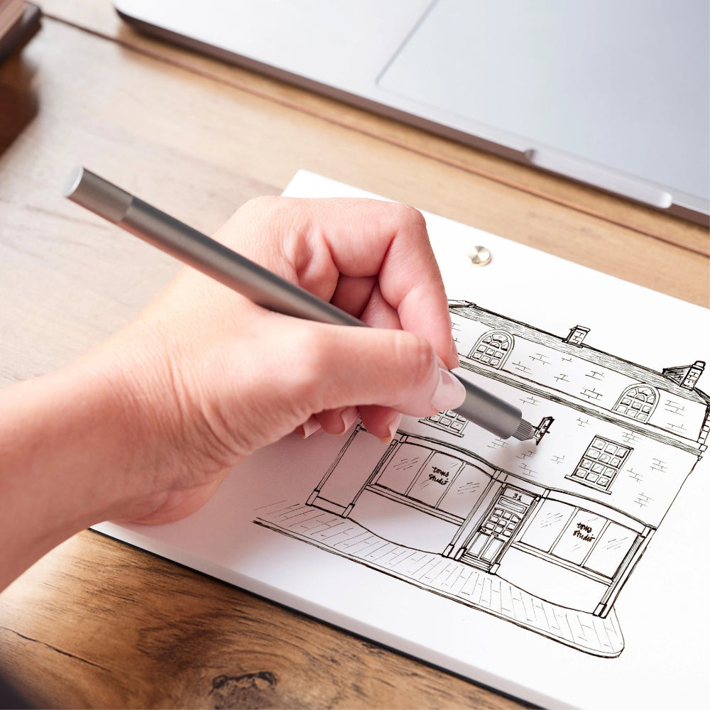 Hand holding a pen over architectural drawings on a wooden desk