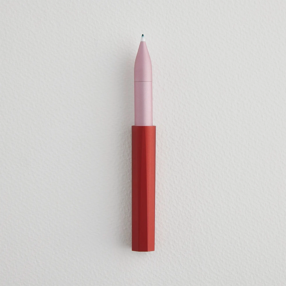 Uncapped pen with red bottom and pink top with ink on the felt tip.
