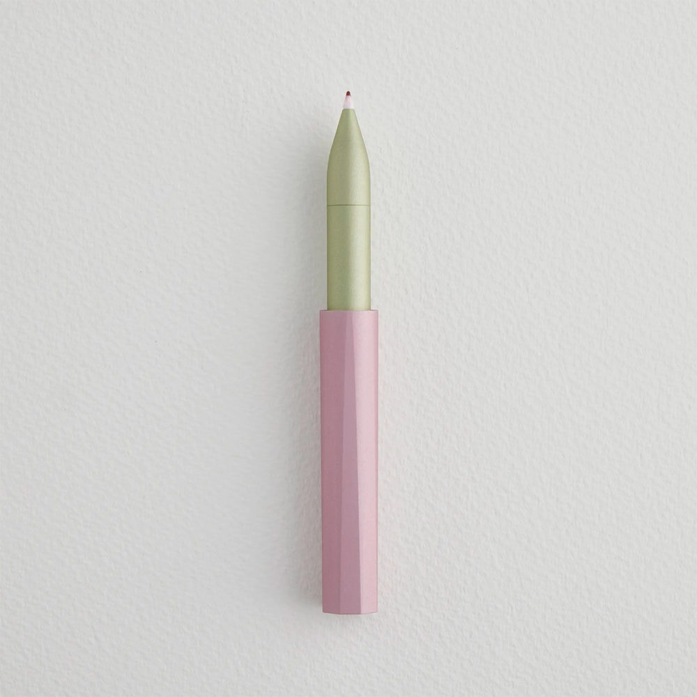 Uncapped pen with pink bottom and light green top with ink on the felt tip.