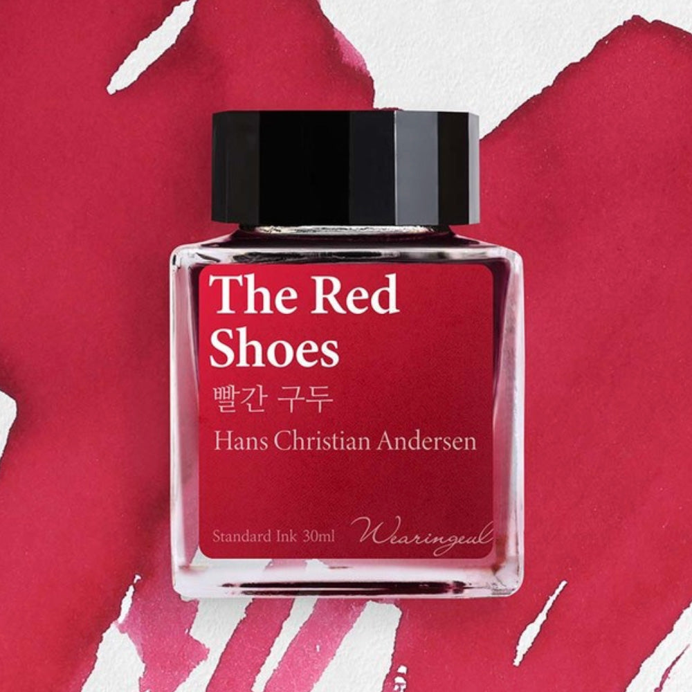Red ink bottle labeled 'The Red Shoes' by Hans Christian Andersen on a red background