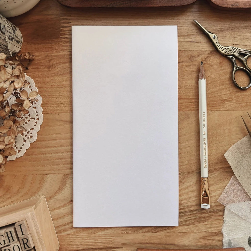 Blank Notebook of paper on a wooden surface with stationery items.