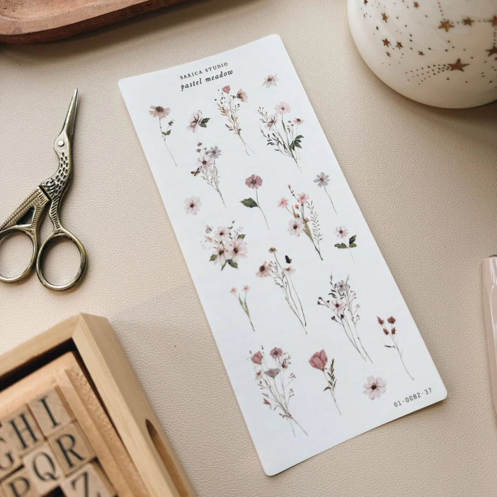 Sheet of floral stickers on a table with scissors and wooden letters.